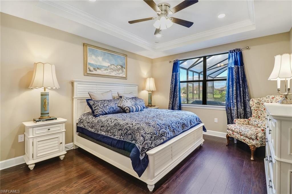 Bedroom featuring dark wood finished floors, ornamental molding, a tray ceiling, a ceiling fan, and recessed lighting