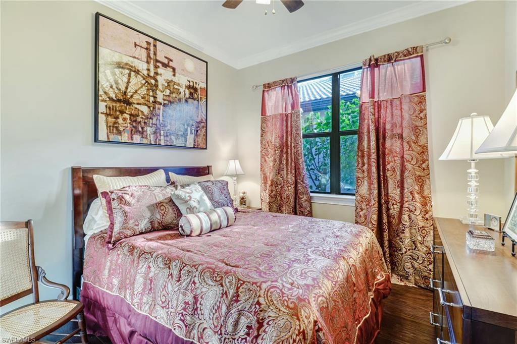 Bedroom featuring dark wood-type flooring, ornamental molding, and a ceiling fan