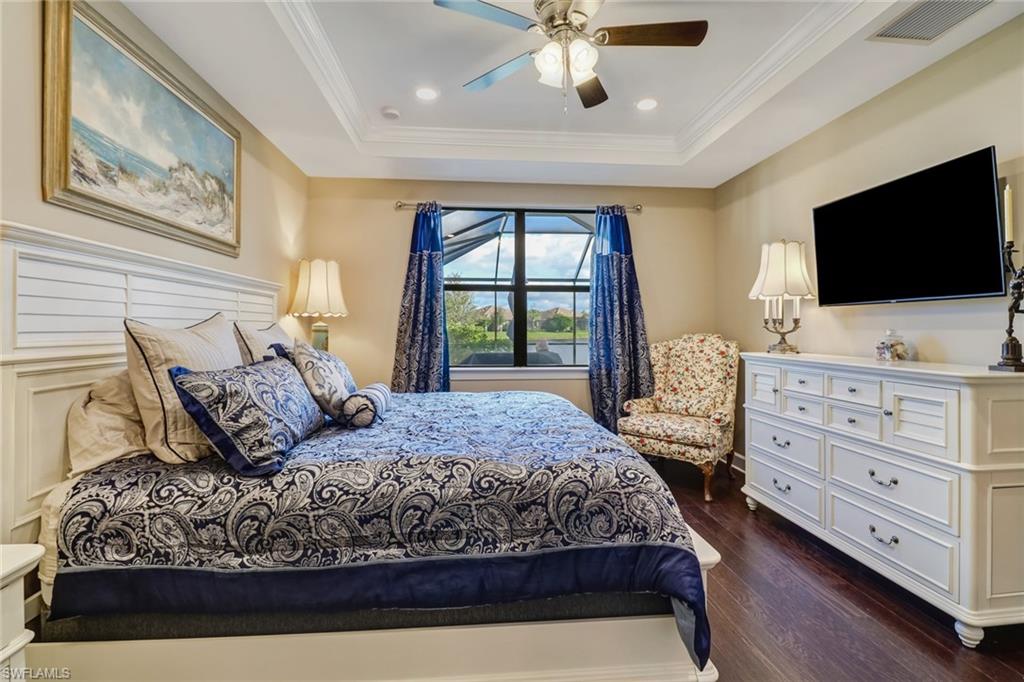 Bedroom with dark wood-type flooring, crown molding, ceiling fan, recessed lighting, and a raised ceiling