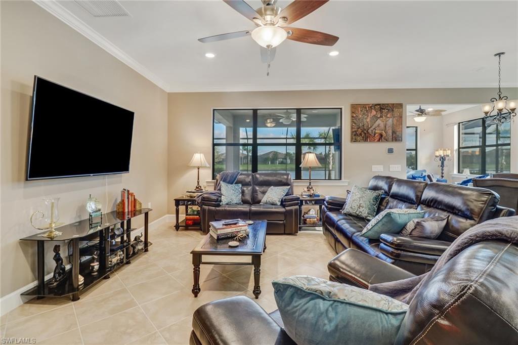 Living room with light tile patterned flooring, crown molding, recessed lighting, a chandelier, and ceiling fan
