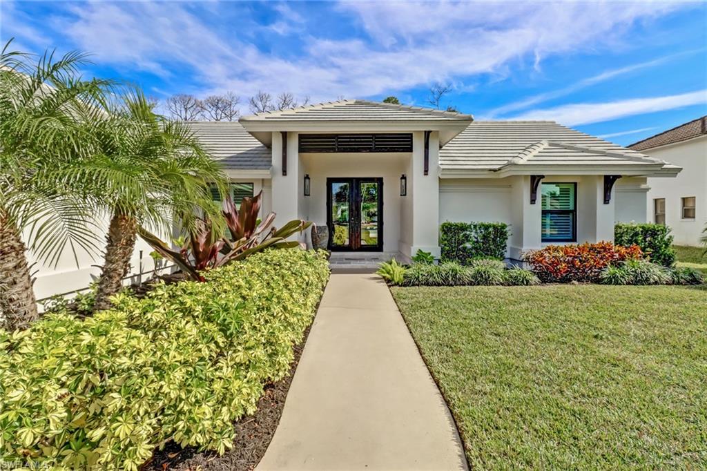 View of exterior entry featuring a tile roof, a yard, french doors, and stucco siding