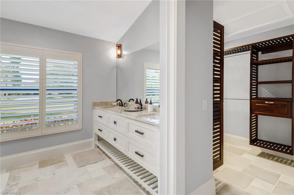 Full bathroom with double vanity and vaulted ceiling