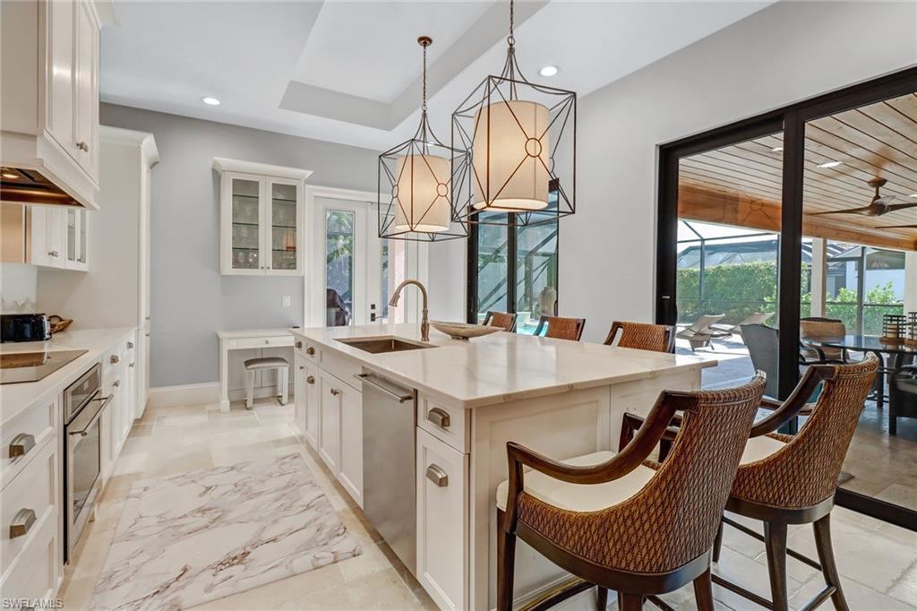 Kitchen featuring a breakfast bar area, white cabinets, glass insert cabinets, light stone counters, and recessed lighting