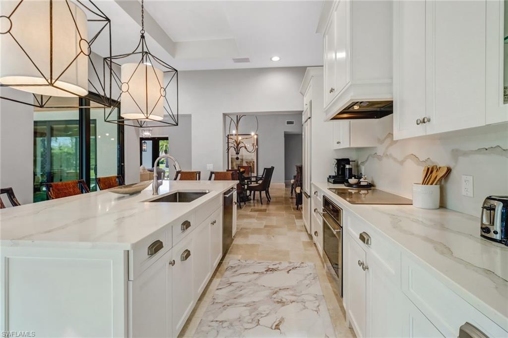 Kitchen featuring white cabinetry, light stone counters, an island with sink, recessed lighting, and stainless steel appliances