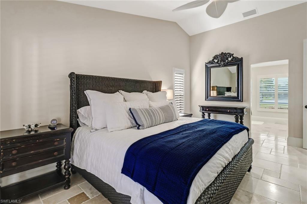Bedroom with stone tile flooring, vaulted ceiling, and a ceiling fan