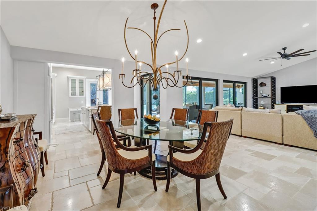 Dining room featuring lofted ceiling, recessed lighting, ceiling fan, stone tile flooring, and a chandelier