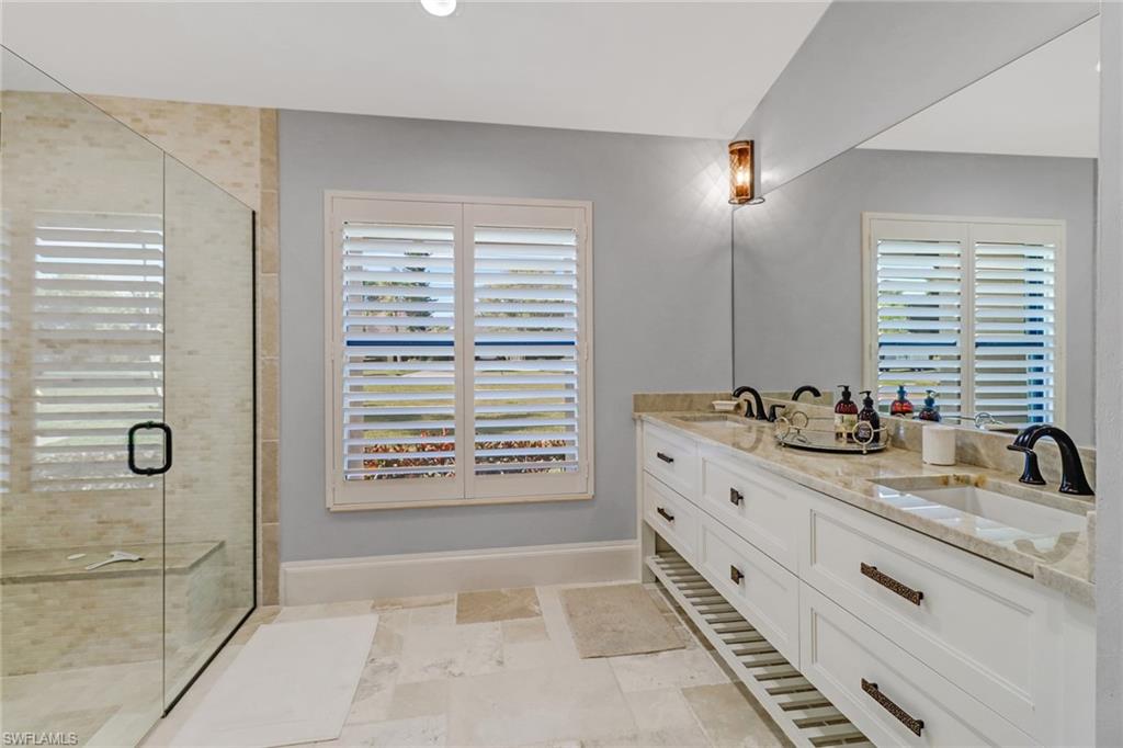 Bathroom with double vanity, a shower stall, and healthy amount of natural light