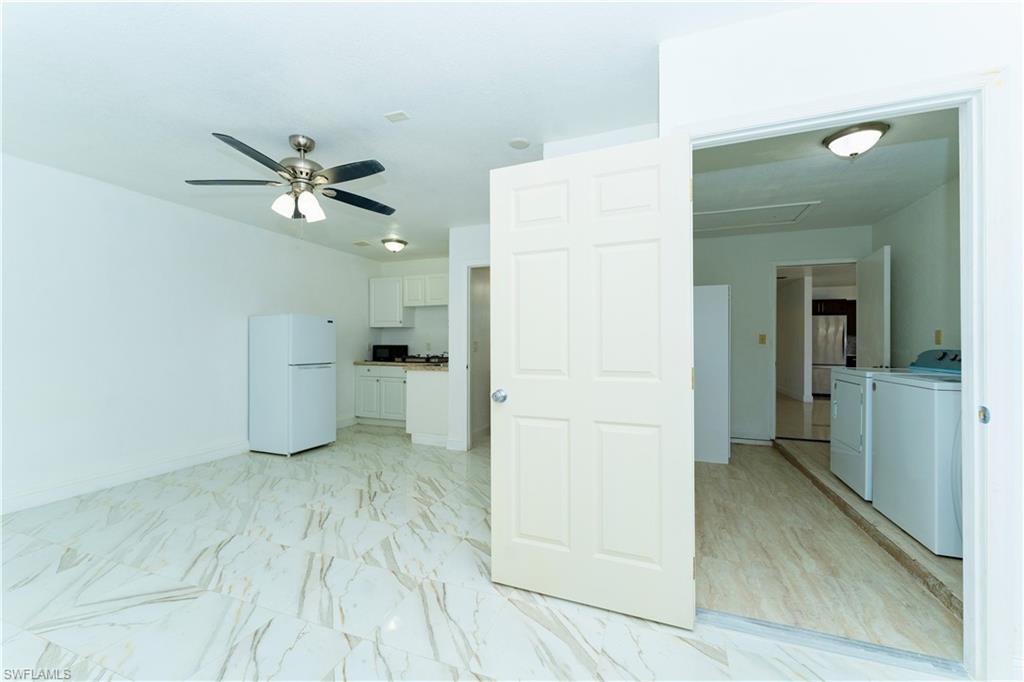Empty room featuring washer and dryer, light marble finish floors, and ceiling fan