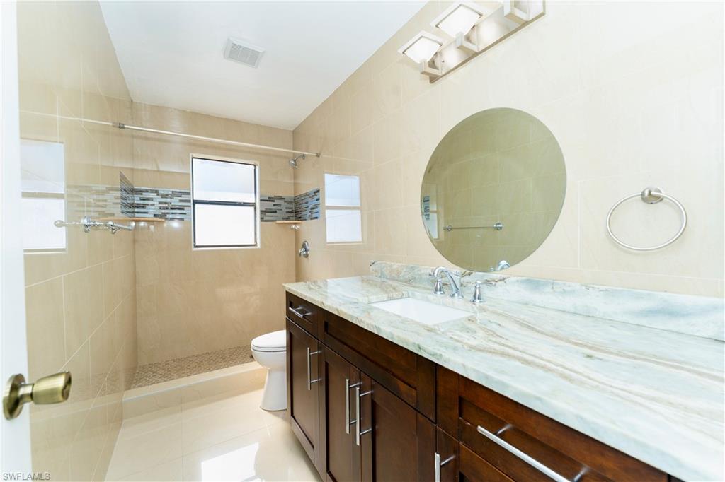 Full bathroom with a walk in shower, vanity, and light tile patterned floors
