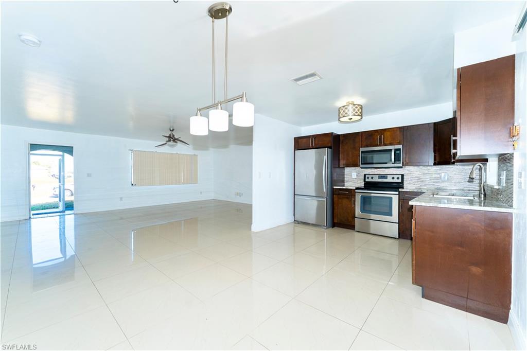 Kitchen with ceiling fan, appliances with stainless steel finishes, pendant lighting, dark brown cabinets, and backsplash