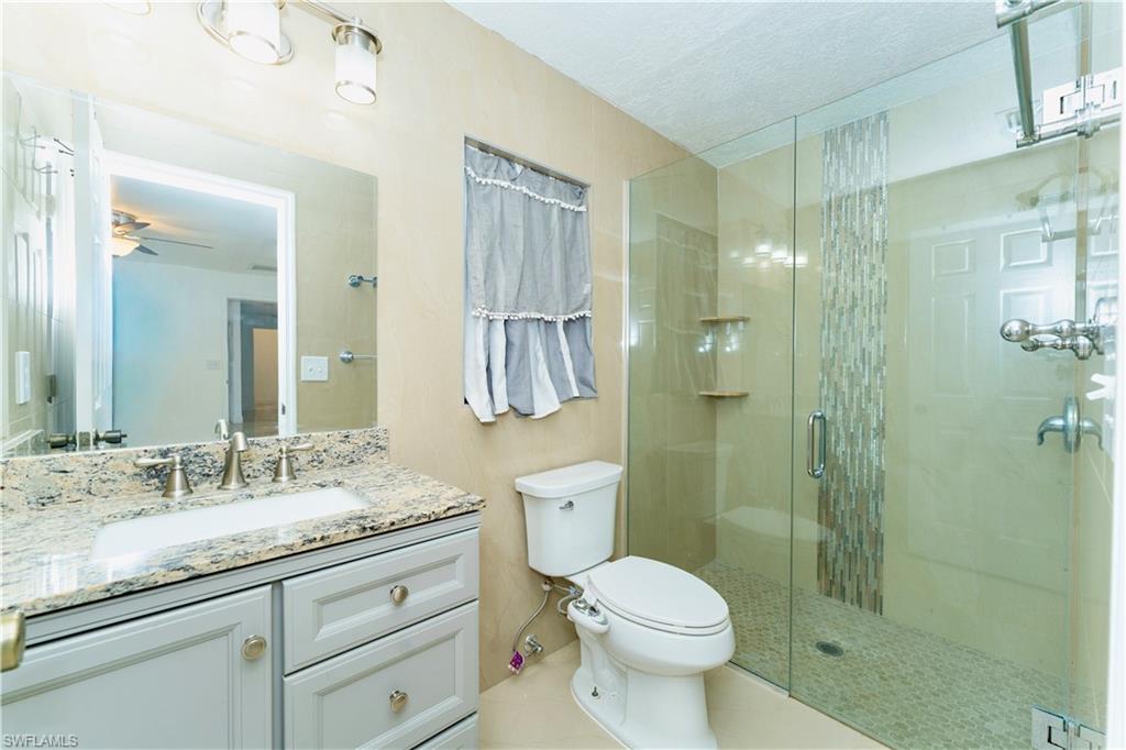 Bathroom with a stall shower, vanity, a textured ceiling, and light tile patterned floors