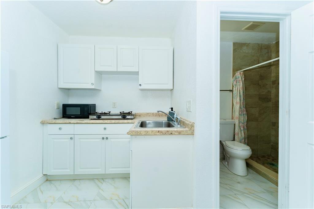 Kitchen with light marble finish floors, white cabinetry, and light countertops
