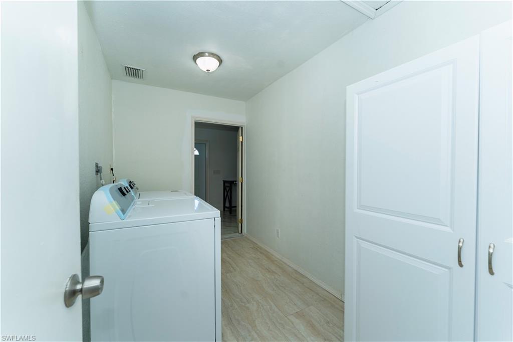 Laundry room with washing machine and dryer and light wood finished floors
