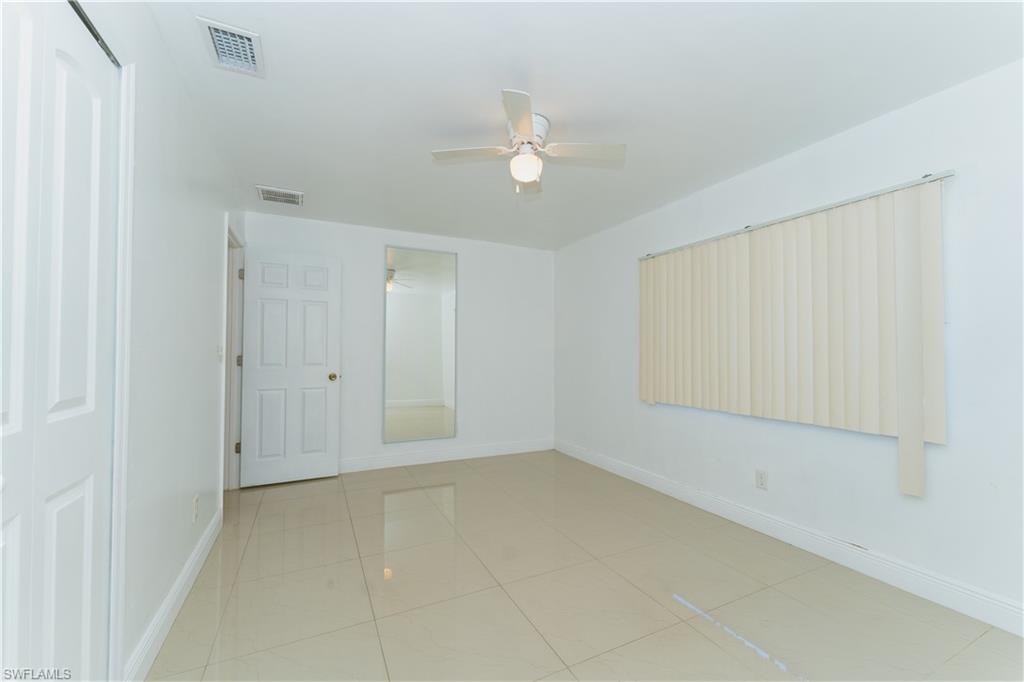 Empty room with light tile patterned floors and a ceiling fan