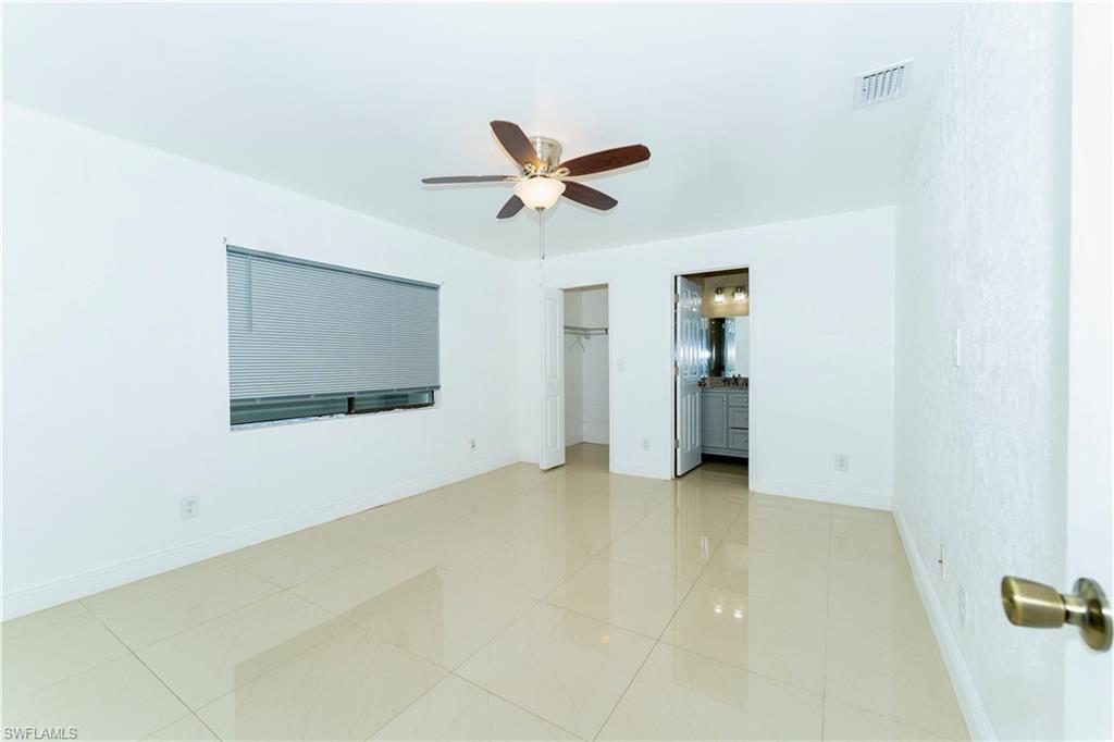 Unfurnished bedroom featuring a closet, ensuite bathroom, ceiling fan, and light tile patterned floors