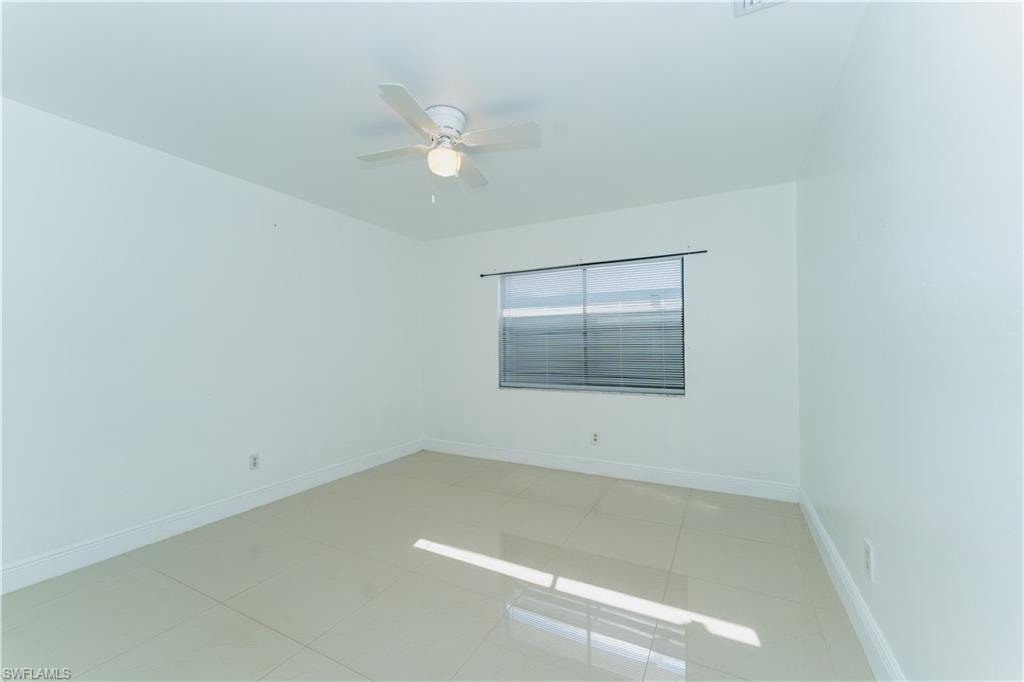 Empty room with light tile patterned floors and ceiling fan