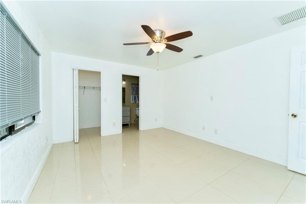 Unfurnished bedroom featuring ceiling fan, a spacious closet, and ensuite bath