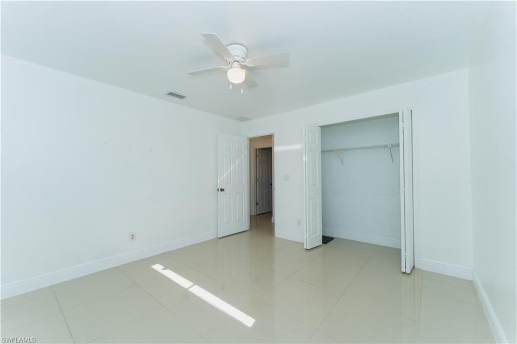 Unfurnished bedroom featuring a ceiling fan, a closet, and light tile patterned floors
