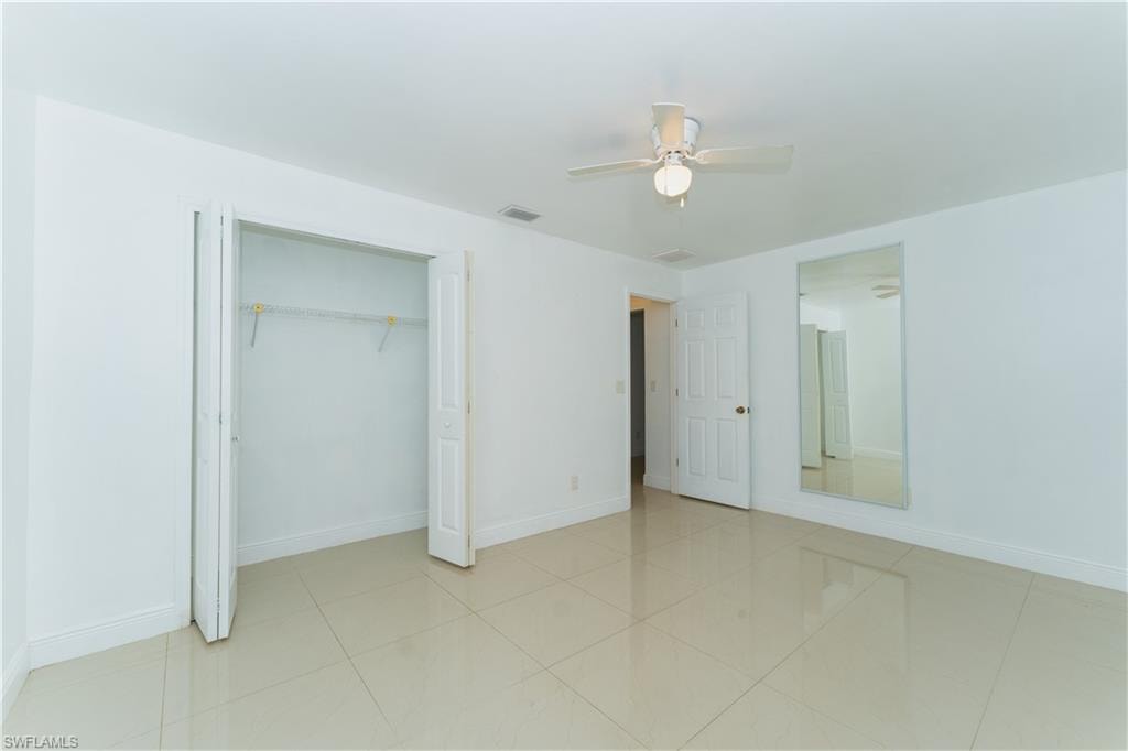Unfurnished bedroom with ceiling fan, a closet, and light tile patterned flooring