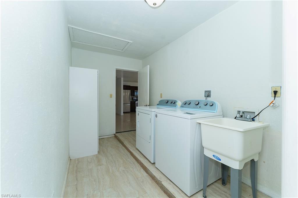 Laundry area with separate washer and dryer, light wood finished floors, and attic access