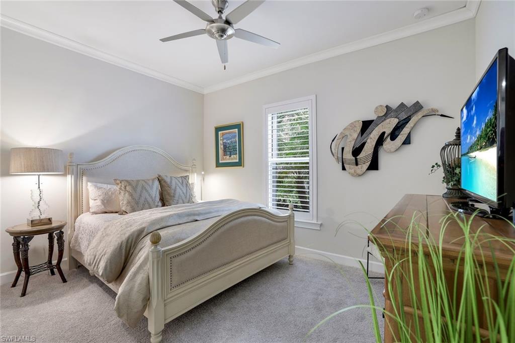 Carpeted bedroom featuring ceiling fan and crown molding