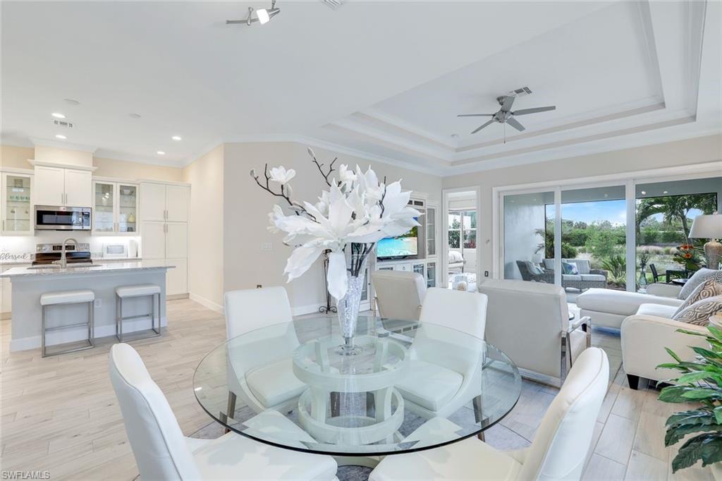 Dining space featuring ceiling fan, sink, light hardwood / wood-style flooring, crown molding, and a tray ceiling