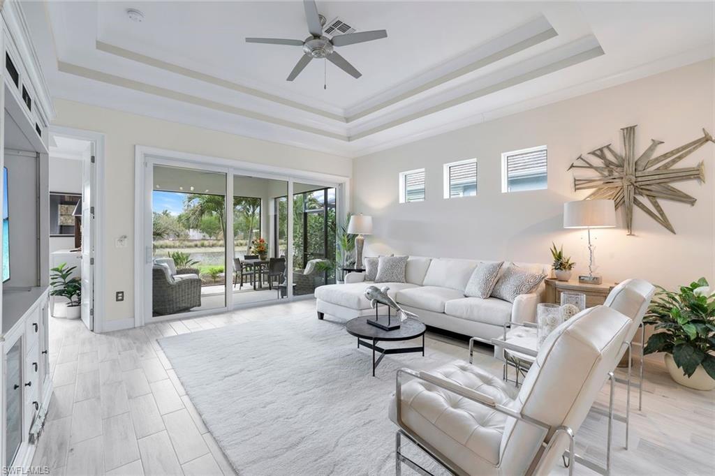 Living room with a tray ceiling, ceiling fan, and ornamental molding