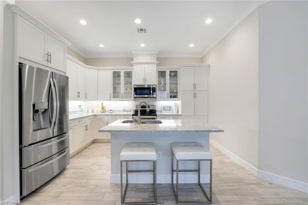 Kitchen with white cabinets, sink, an island with sink, and appliances with stainless steel finishes
