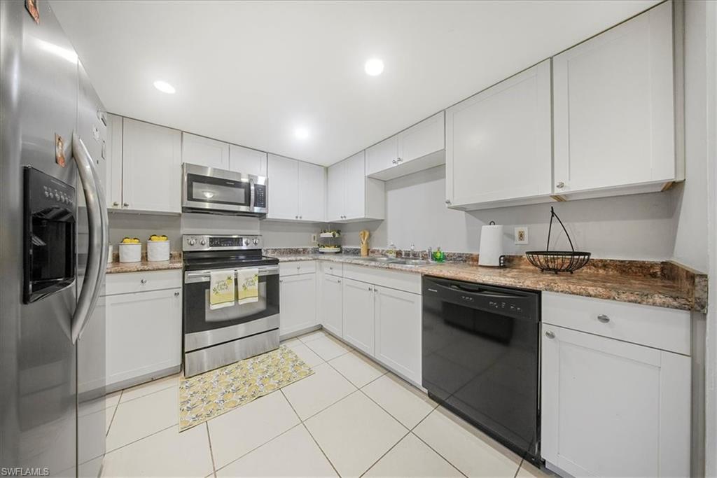 Kitchen featuring stainless steel appliances, white cabinets, light tile patterned floors, recessed lighting, and light stone counters