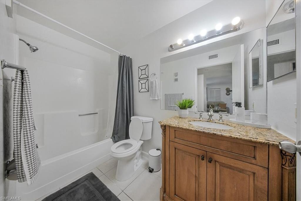 Bathroom with light tile patterned floors, vanity, and shower / bath combo