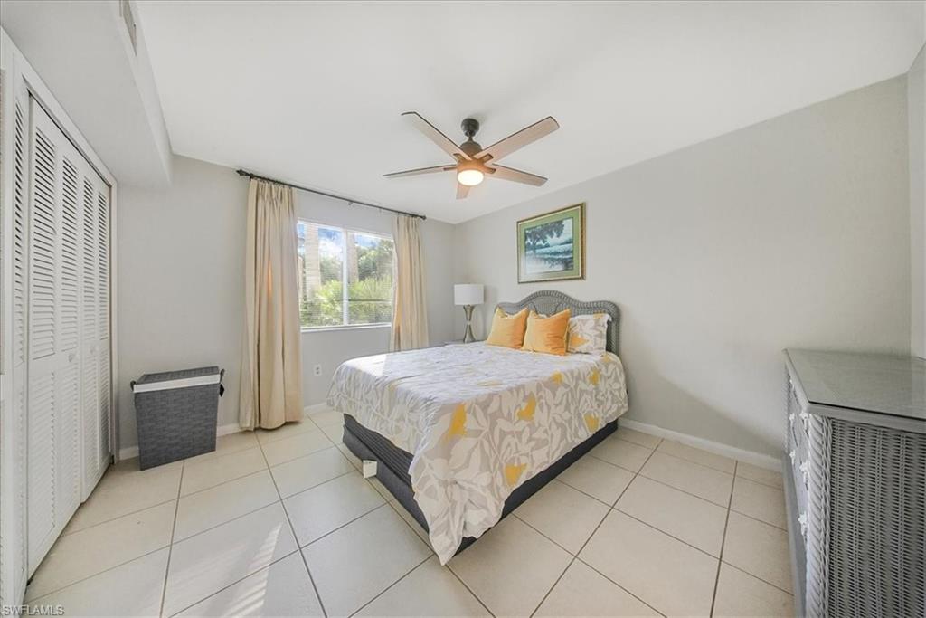 Bedroom with a ceiling fan, light tile patterned floors, and a closet