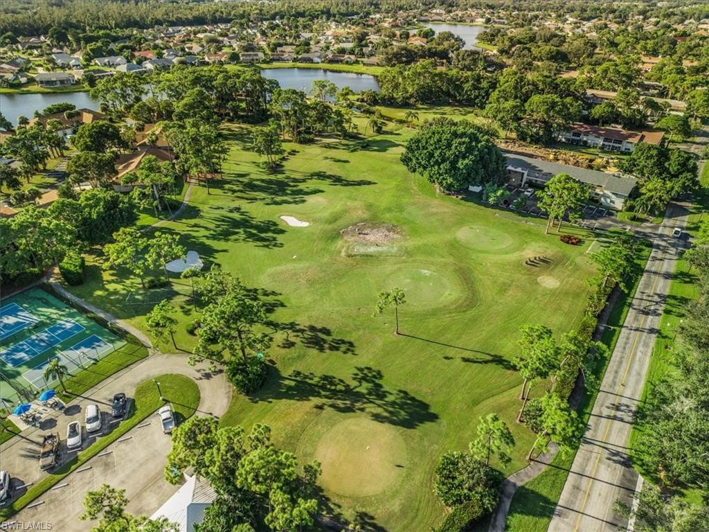 Aerial perspective of suburban area featuring a nearby body of water and a golf course