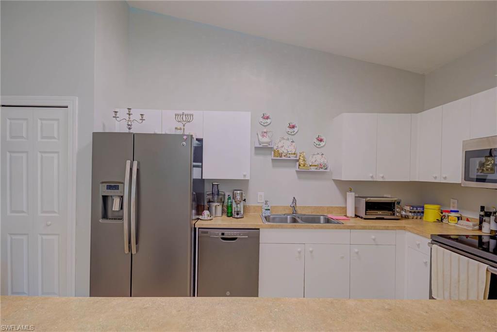Kitchen with stainless steel appliances, light countertops, and white cabinets