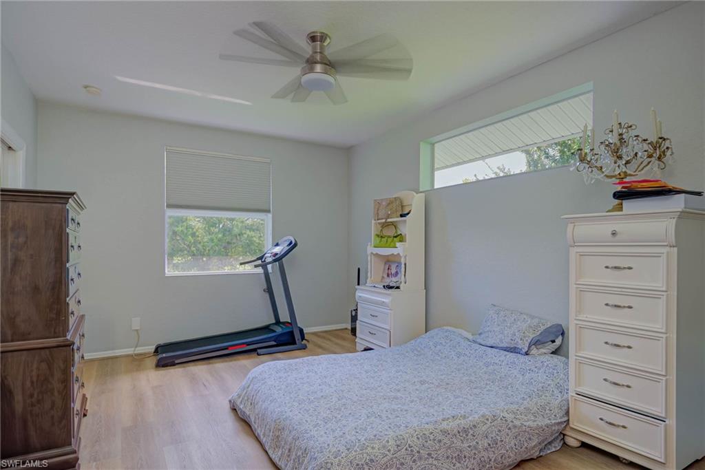 Bedroom with multiple windows, light wood-style flooring, and ceiling fan