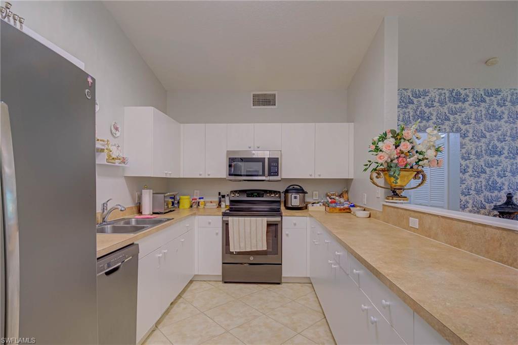 Kitchen with appliances with stainless steel finishes, light countertops, white cabinets, and light tile patterned floors
