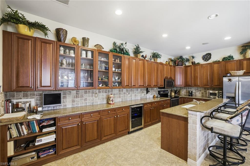 Kitchen showing glass paned cabinetry, granite countertops, wine cooler