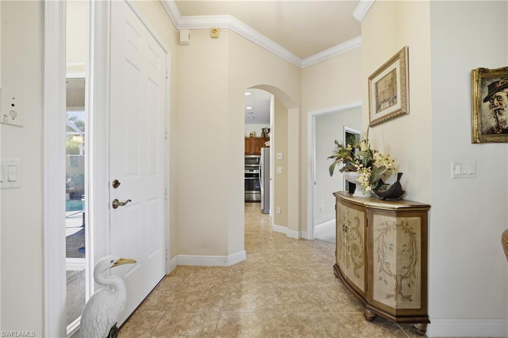 Foyer featuring arched walkways, crown molding, and light tile patterned floors
