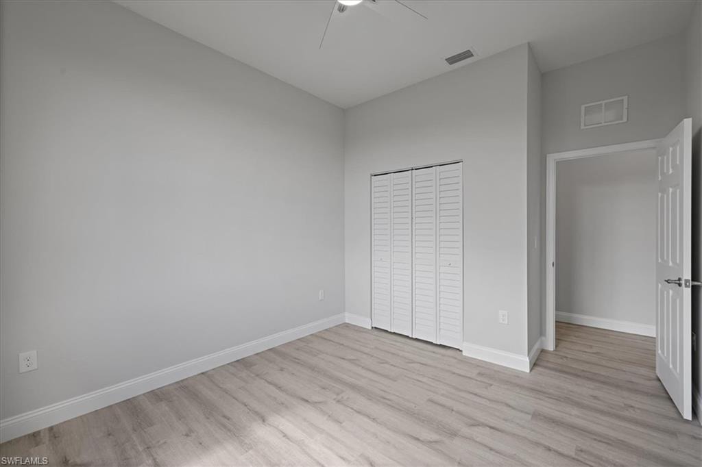 Unfurnished bedroom featuring light wood-style floors, a closet, and ceiling fan