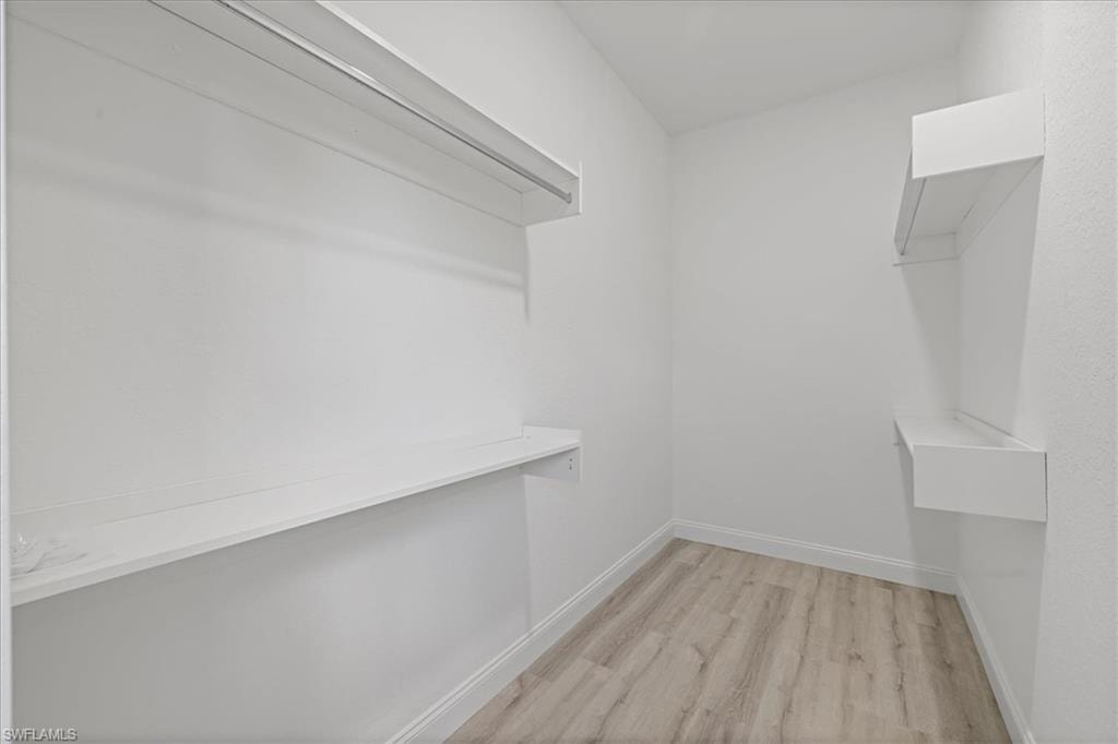 Walk in closet with light wood-style floors