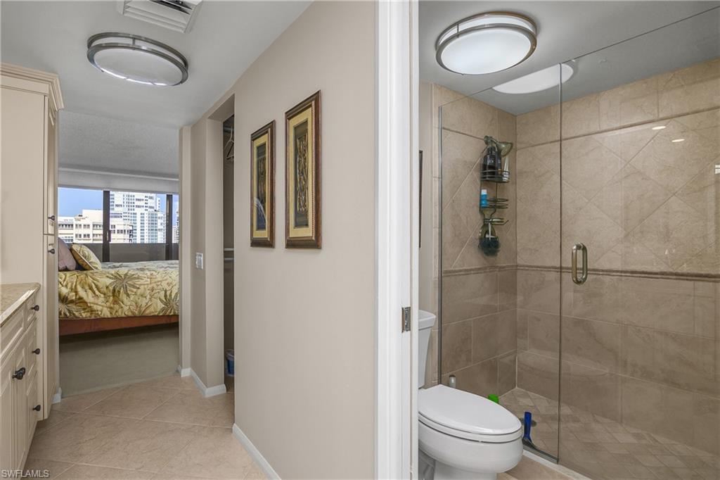 Ensuite bathroom featuring light tile patterned flooring, a shower stall, and vanity