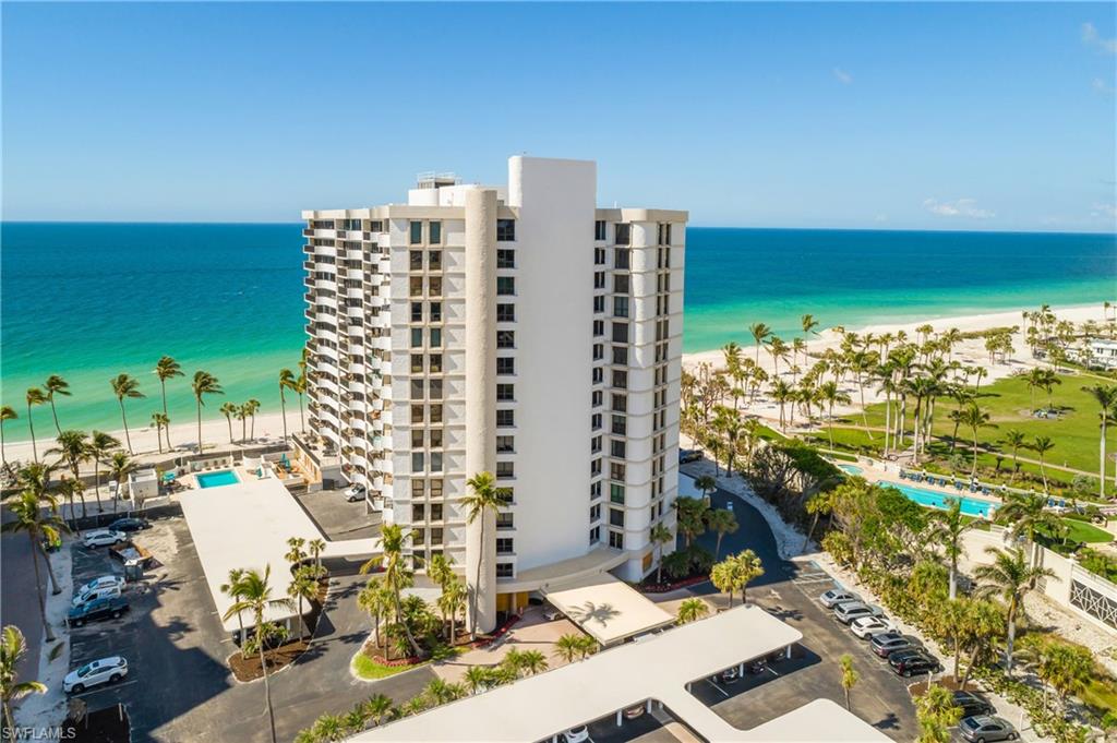 Drone / aerial view of apartment complex and waterfront with a beach
