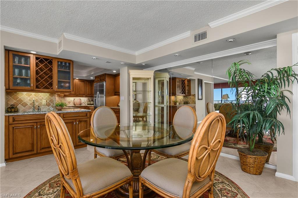 Dining area with ornamental molding, light tile patterned floors, a textured ceiling, a raised ceiling, and recessed lighting