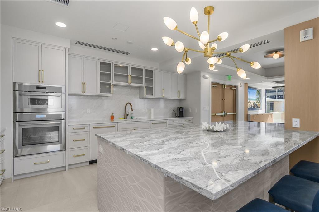 Social Room kitchen with a breakfast bar, decorative light fixtures, backsplash, light stone counters, and recessed lighting