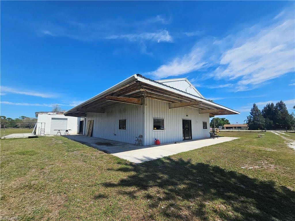 Back of house with metal roof, a yard, and a patio area