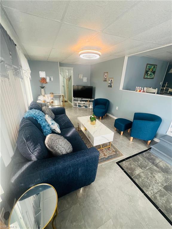 Living area featuring a drop ceiling and baseboards