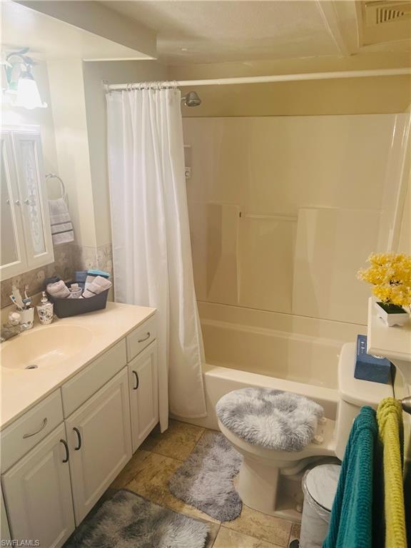 Bathroom with vanity, shower / bath combo, and light tile patterned flooring