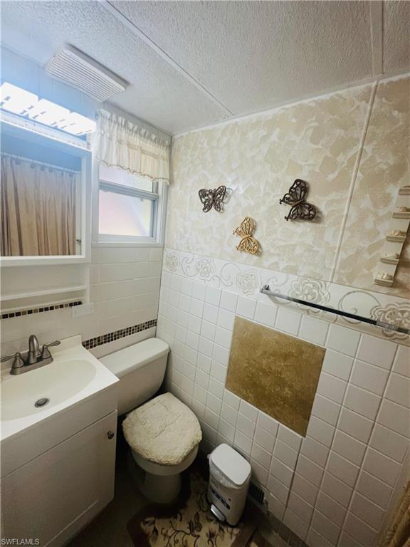 Bathroom featuring tile walls, vanity, and a textured ceiling