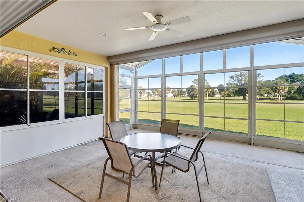 Sunroom with view of golf course, ceiling fan, and outdoor dining space