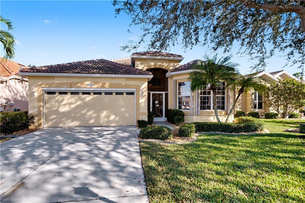 Mediterranean / spanish home featuring an attached garage, driveway, stucco siding, a front lawn, and a tile roof