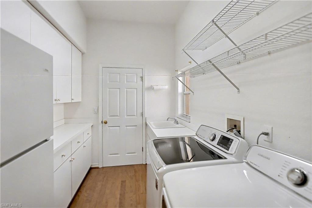 Washroom with wood finished floors, cabinet space, and independent washer and dryer